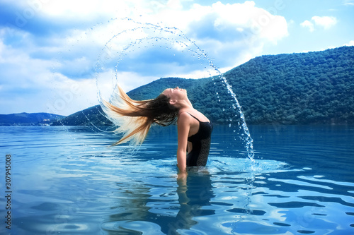 Beautiful girl splashing in the water. Retreat. Vacation. Colorful blue landscape. Rest, relax in nature. Enjoy life. Lifestyle. A young woman swimming in the sea. Color of the year 2020. Tropical.