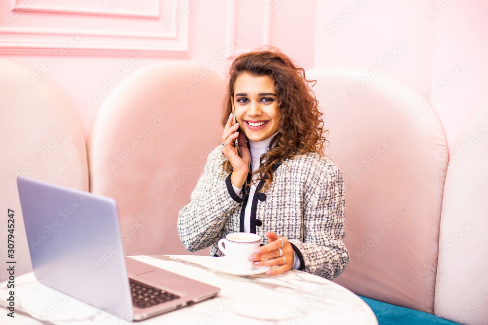 Happy young woman sitting at the table and talking on the phone in cafe. Happy young woman sitting at the table and talking on the phone in cafe.