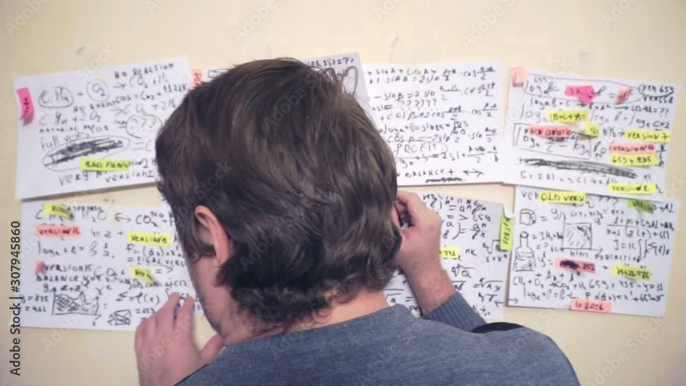 researcher works with various information on paper sheets that hang on the wall.research work. scientist in the workplace researcher works with various information on paper sheets that hang on the wall.research work. scientist in the workplace