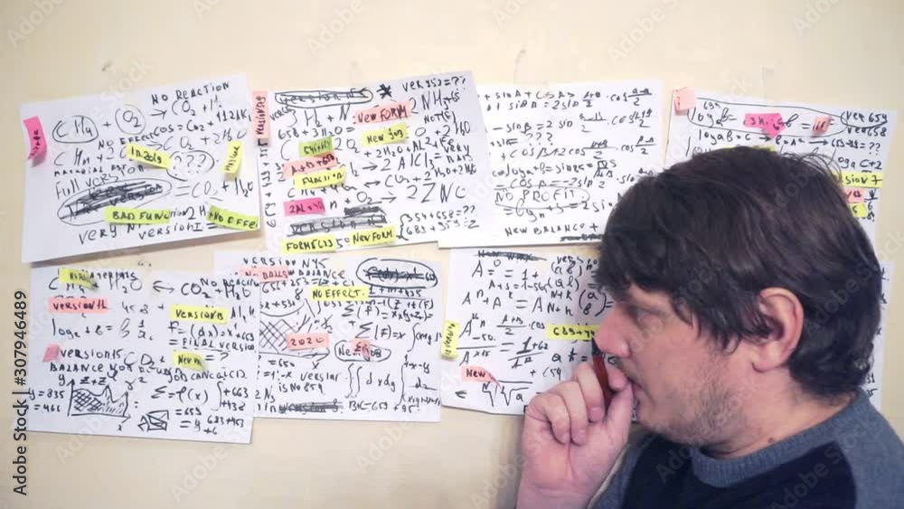 researcher works with various formulas and calculations on paper sheets that hang on the wall.research work.scientist in the workplace researcher works with various formulas and calculations on paper sheets that hang on the wall.research work.scientist in the workplace
