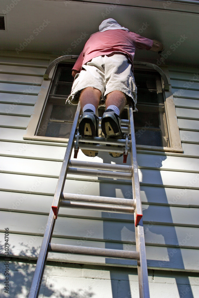 Looking Up At Man On a Ladder Painting a House