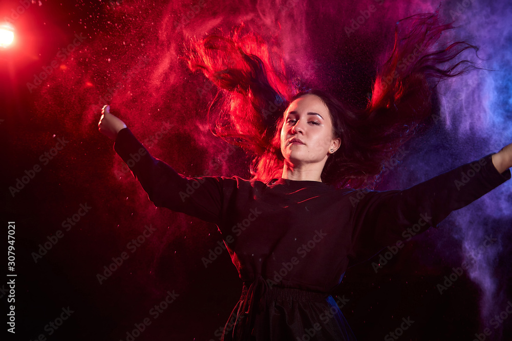 Plump teen girl during a photo shoot with flour with colored backlight and black background. Teenage model posing at night
