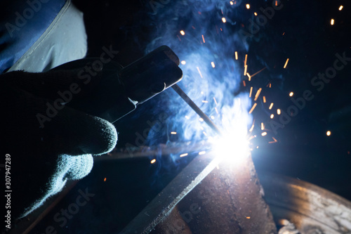 Man welder cooks metal. Sparks from the welding machine.