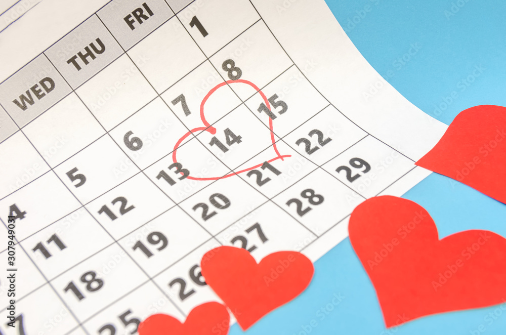 Valentine's day 14 is marked with a heart on the calendar, paper hearts are scattered around. Holiday concept Valentine's day 14 is marked with a heart on the calendar, paper hearts are scattered around. Holiday concept