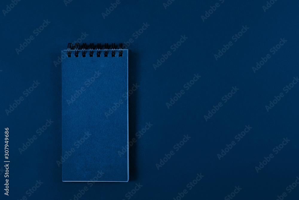 Blank page of a notebook on spiral on plain background, top view. Trendy banner with color of the year 2020 - Classic Blue. Blank page of a notebook on spiral on plain background, top view. Trendy banner with color of the year 2020 - Classic Blue.