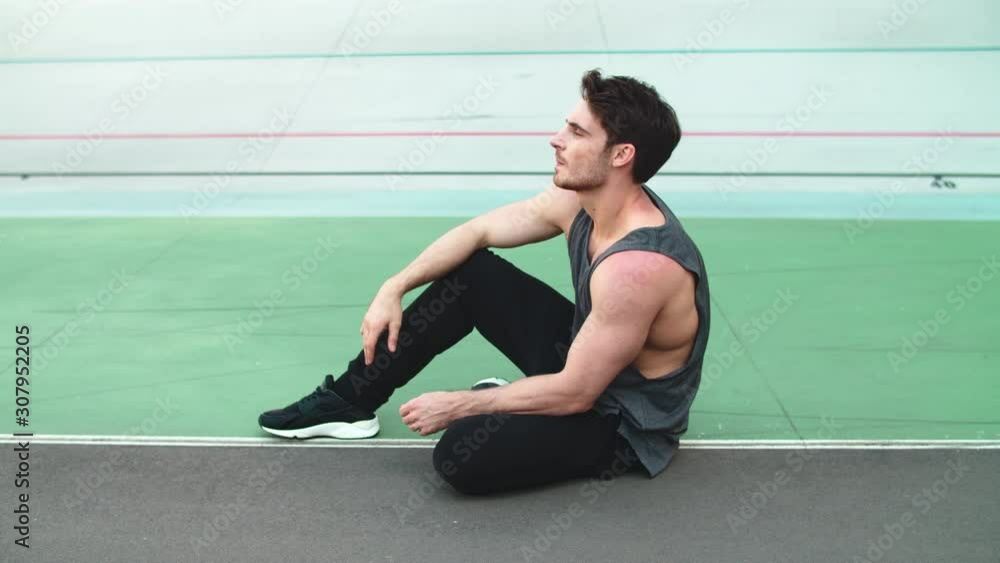 Tired runner sitting after workout on track. Exhausted man resting after workout Tired runner sitting after workout on track. Exhausted man resting after workout