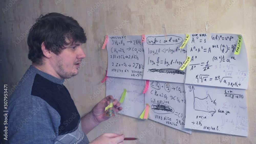 man works with various formulas and calculations on paper sheets that hang on the wall.research work. teacher in the workplace. man works with various formulas and calculations on paper sheets that hang on the wall.research work. teacher in the workplace.