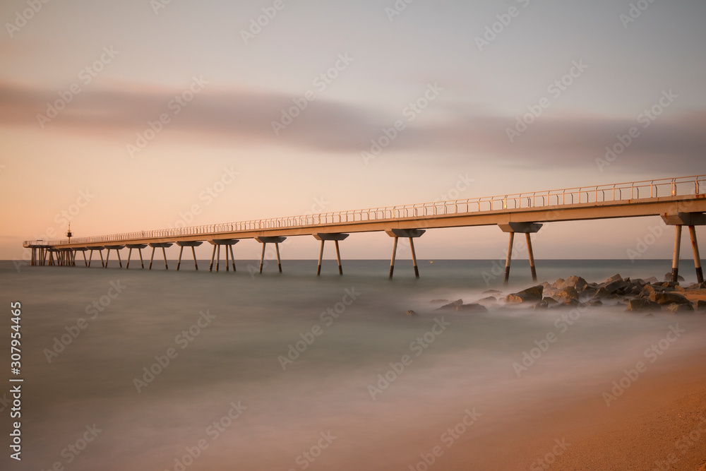 a long pier above the sea illuminated by the early morning sun 