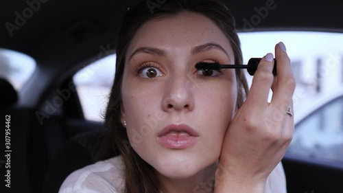 The woman in the car does makeup. Beautiful female portrait close-up while applying mascara to lashes