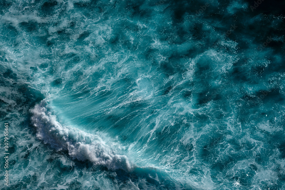 Aerial view to seething waves with foam backlit by the setting sun. Bali, Indonesia.