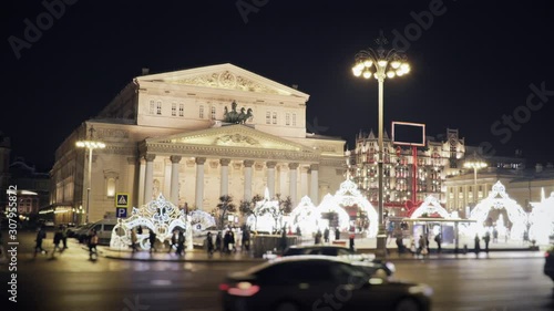 Beautiful view to the Bolshoi Theatre on a winter night all in Christmas decorations, with cars and pedestrians passing by in front of it and TsUM glittering on the background.  photo