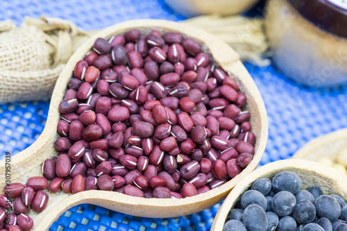 Raw azuki beans on wooden scoop over blue background