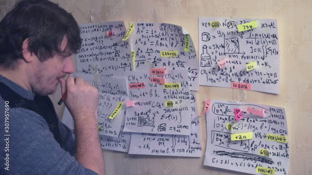 researcher works with various formulas and calculations on paper sheets that hang on the wall.research work.scientist in the workplace. researcher works with various formulas and calculations on paper sheets that hang on the wall.research work.scientist in the workplace.