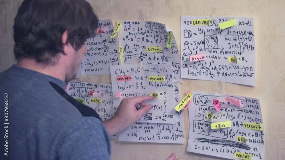 researcher works with various formulas and calculations on paper sheets that hang on the wall.research work.scientist in the workplace. researcher works with various formulas and calculations on paper sheets that hang on the wall.research work.scientist in the workplace.