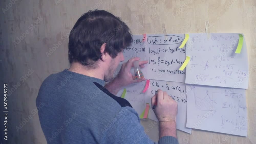 man works with various formulas and calculations on paper sheets that hang on the wall.research work. teacher in the workplace. man works with various formulas and calculations on paper sheets that hang on the wall.research work. teacher in the workplace.