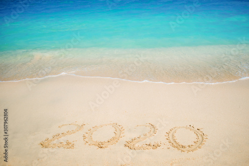 New 2020 year in the South, the sea. Sea surf. Blue wave is coming ashore. Inscription on sand,