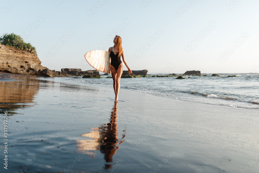 Surfer girl walking with board on the sandy beach. Surfer female.Beautiful young woman at the beach. water sports. Healthy Active Lifestyle. Surfing. Summer Vacation. Extreme Sport.