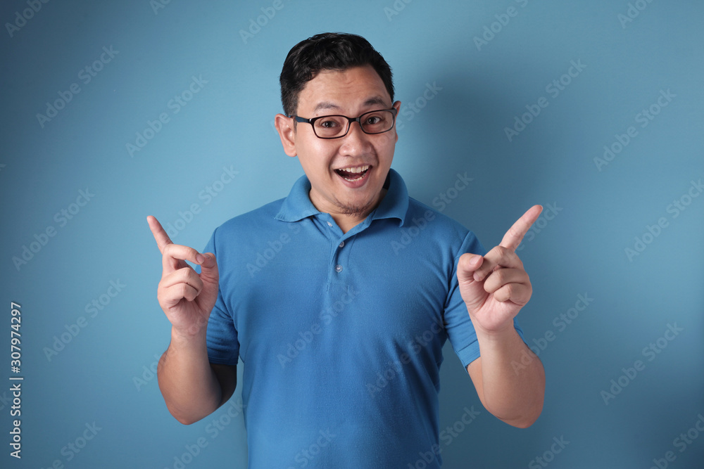 Young Man Pointing Two Fingers Up, Thinking and Looking Up, Having Good Idea Young Man Pointing Two Fingers Up, Thinking and Looking Up, Having Good Idea