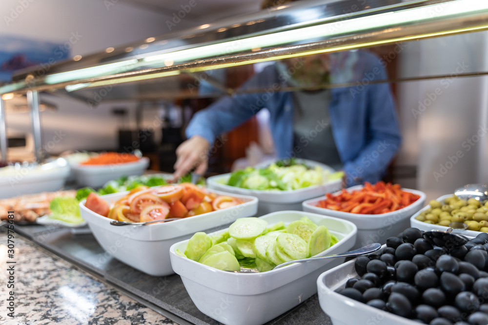 Plates of healthy food, olives and salad and an unfocused background man picking up food. Plates of healthy food, olives and salad and an unfocused background man picking up food.