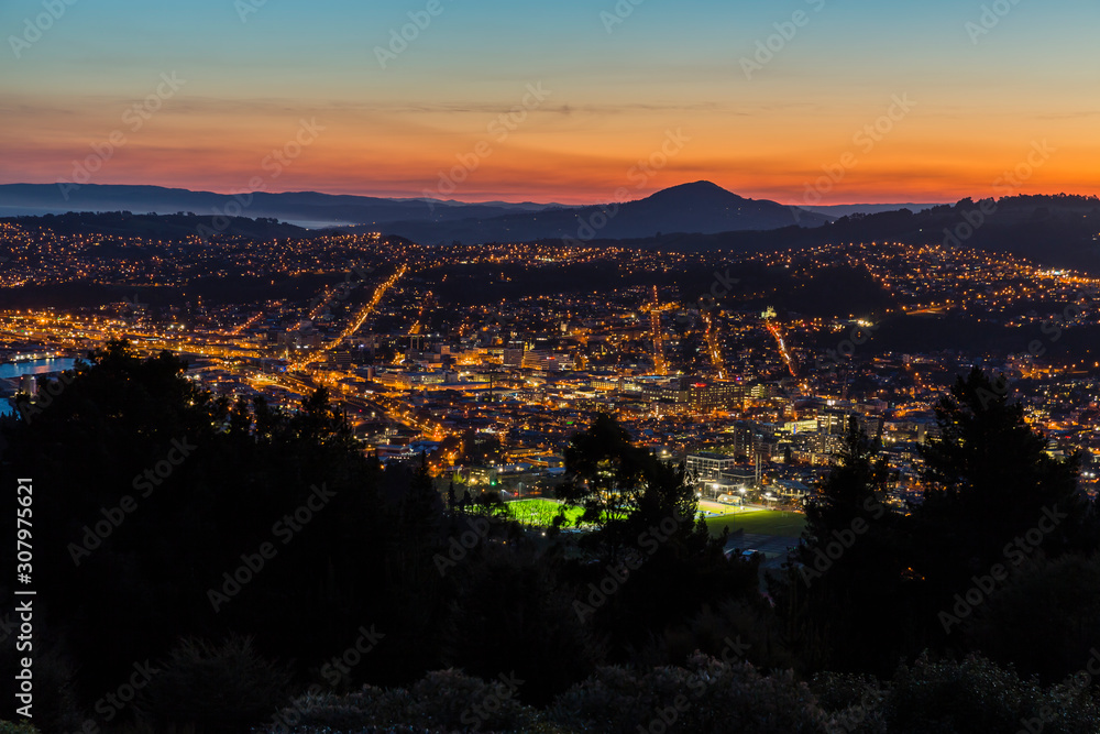 Obraz premium ニュージーランド ダニーデンのシグナル・ヒル・ルックアウトから見える夕焼けに染まった空とダニーデンの夜景