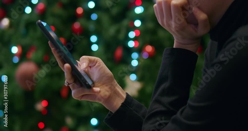 Asian woman using smartphone texting and shopping online while sitting near christmas tree at night.Technology communication business.close up shot.
