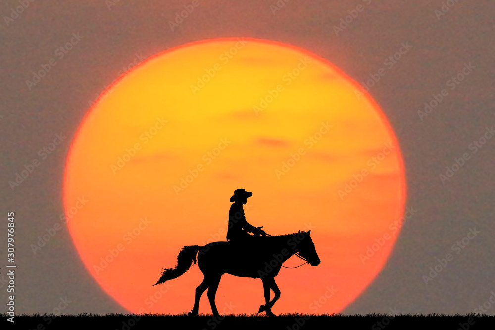 silhouette cowboy riding a horse on sunrise