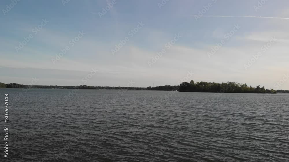Beautiful view of a calm lake with blue sky and waves that are drawn over the surface of the water, the trees on the sides accompany the scene Beautiful view of a calm lake with blue sky and waves that are drawn over the surface of the water, the trees on the sides accompany the scene