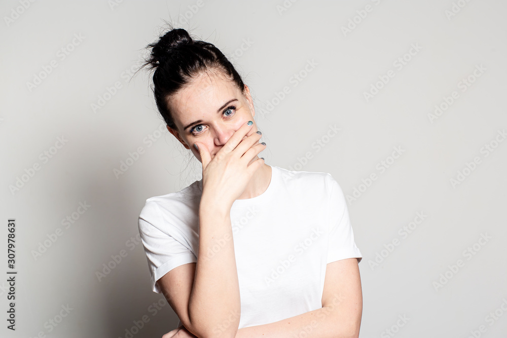 Charming young woman sincerely laughs, closes her mouth with her hand and looks at the camera cheerfully. Charming young woman sincerely laughs, closes her mouth with her hand and looks at the camera cheerfully.
