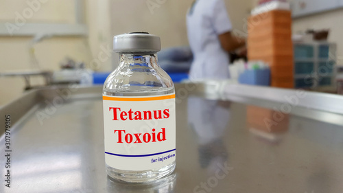 Medical bottle of Tetanus vaccine with blurred background of nurse dressing wound. Tetanus toxoid (TT) used to prevent tetanus infection or lockjaw disease cause from bacteria found in soil, rust.