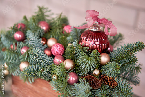 Closeup details of Small arrangement of fresh spruce in a rustic wooden box. Christmas mood. Bokeh of Garland  lamps lights on background.