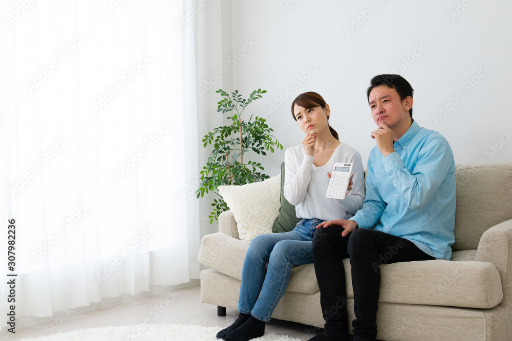 電卓を持って家計を相談する夫婦 電卓を持って家計を相談する夫婦