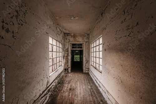 Corridor in abandoned building with old white ragged walls and windows bars