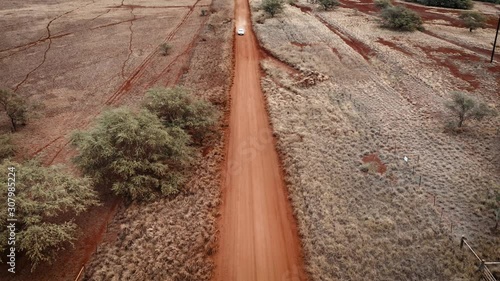 Aerial over two white cars chasing or following each other on a dirt road in Molokai, Hawaii from Maunaloa to Hale o Lono. photo