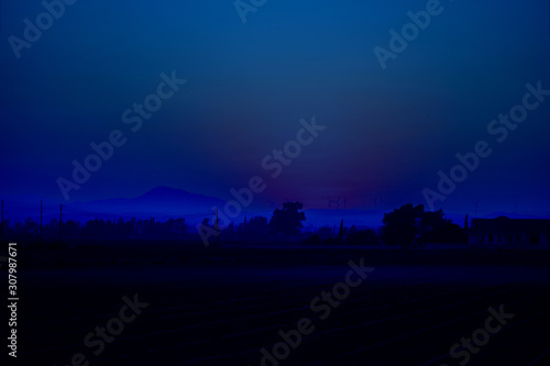 Sunrise over the farm field, sky, fog, downy mildew, mountains, wind turbines. Horizontal. Mideterranian, cyprus, agriculture, ecology. Classic, blue monochrome, trend 2020 photo