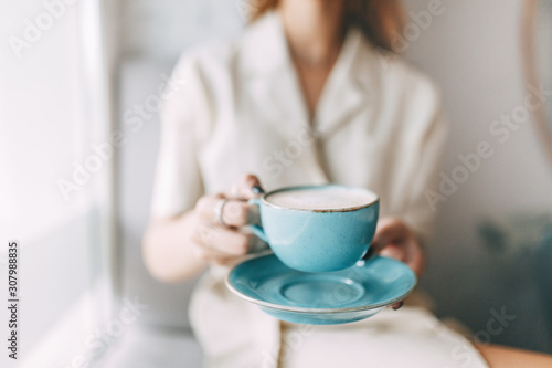  atmospheric coffee shop and stylish dishes. hot mug of coffee in the hands of a young girl.