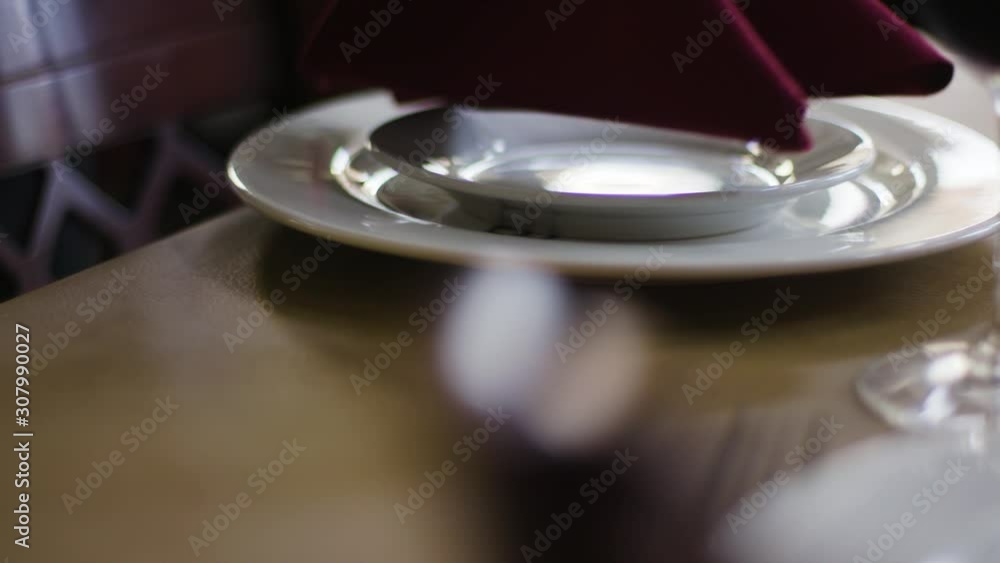 A server sets a table at a high end fancy restaurant. A server sets a table at a high end fancy restaurant.
