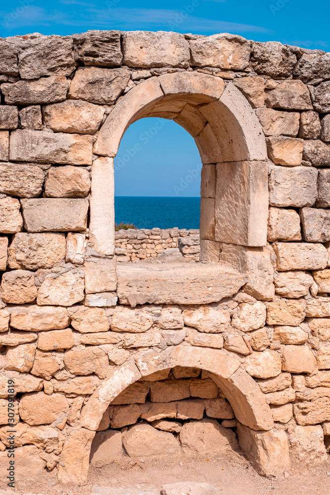 antique stone wall with arched opening and sea view