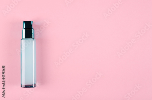 Beauty cream in glass bottle on pink background.