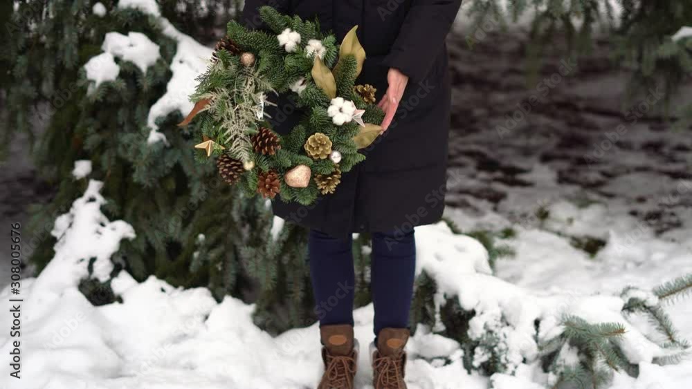 Legs in boots of the girl with christmas wreath in hands. Snowy winter day Legs in boots of the girl with christmas wreath in hands. Snowy winter day