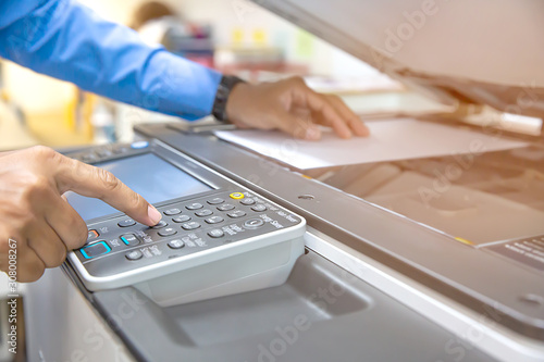 Businessmen press button on the panel of photocopier or printer for printout, scanning, exrox documents papers at office workplace.