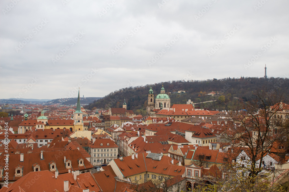 Obraz premium Panorama of the Czech city of Prague with tiled orange roofs from the observation deck of Prague Castle on a cloudy day on the eve of Christmas.