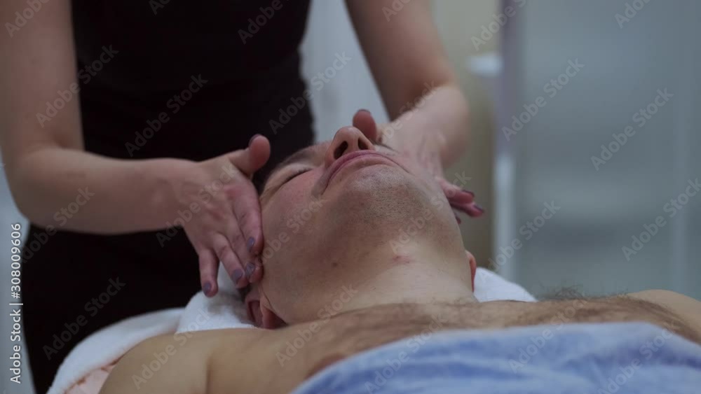 Adult man is having cosmetic treatment at spa salon. Cosmetologist medical gloves is touching face. facial cleansing with professional cosmetic facial massage. Applying the mask to the face. anti-age Adult man is having cosmetic treatment at spa salon. Cosmetologist medical gloves is touching face. facial cleansing with professional cosmetic facial massage. Applying the mask to the face. anti-age