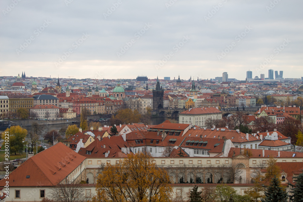 Fototapeta premium Panorama of the Czech city of Prague with tiled orange roofs from the observation deck of Prague Castle on a cloudy day on the eve of Christmas.