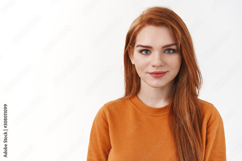 Close-up studio shot pretty redhead woman with long hair, wear orange sweater, smiling and looking camera enthusiastic, listening someone talking, having relaxing conversation, white background