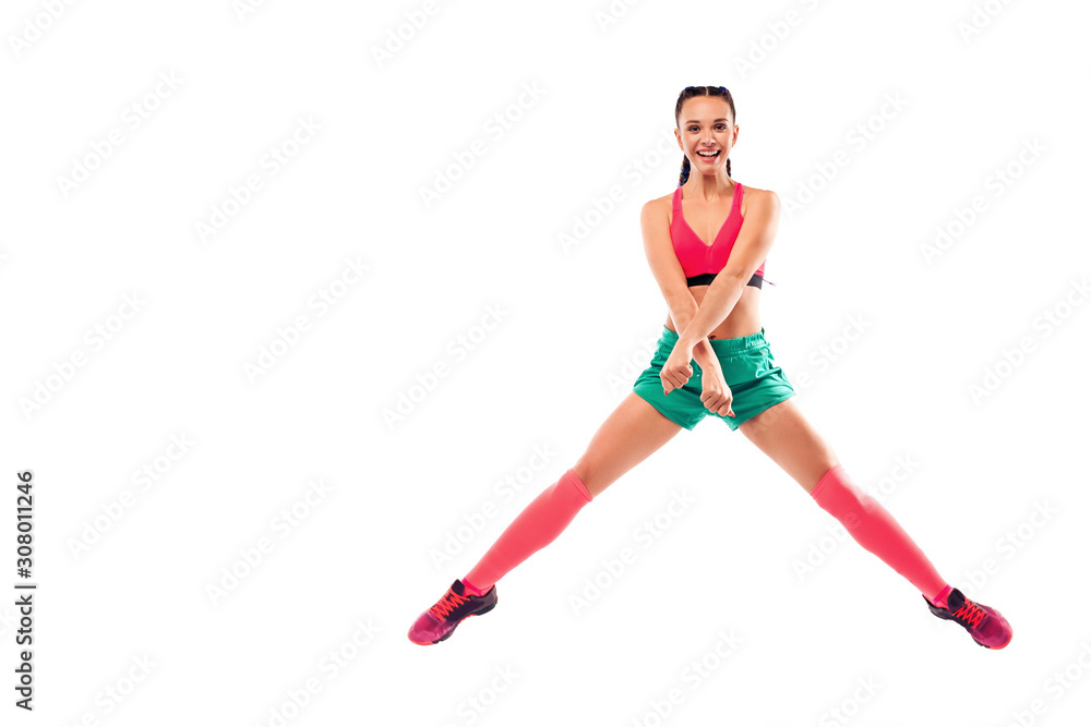 Fototapeta premium Cheerful young female jumping and dancing zumba on white background.