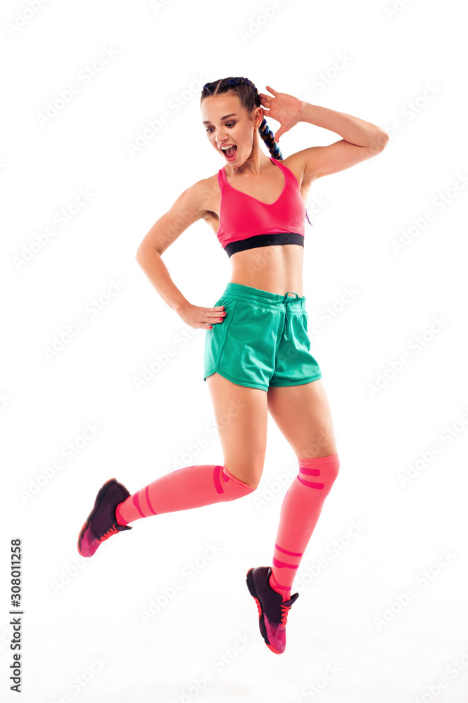 Cheerful young female jumping and dancing zumba on white background.