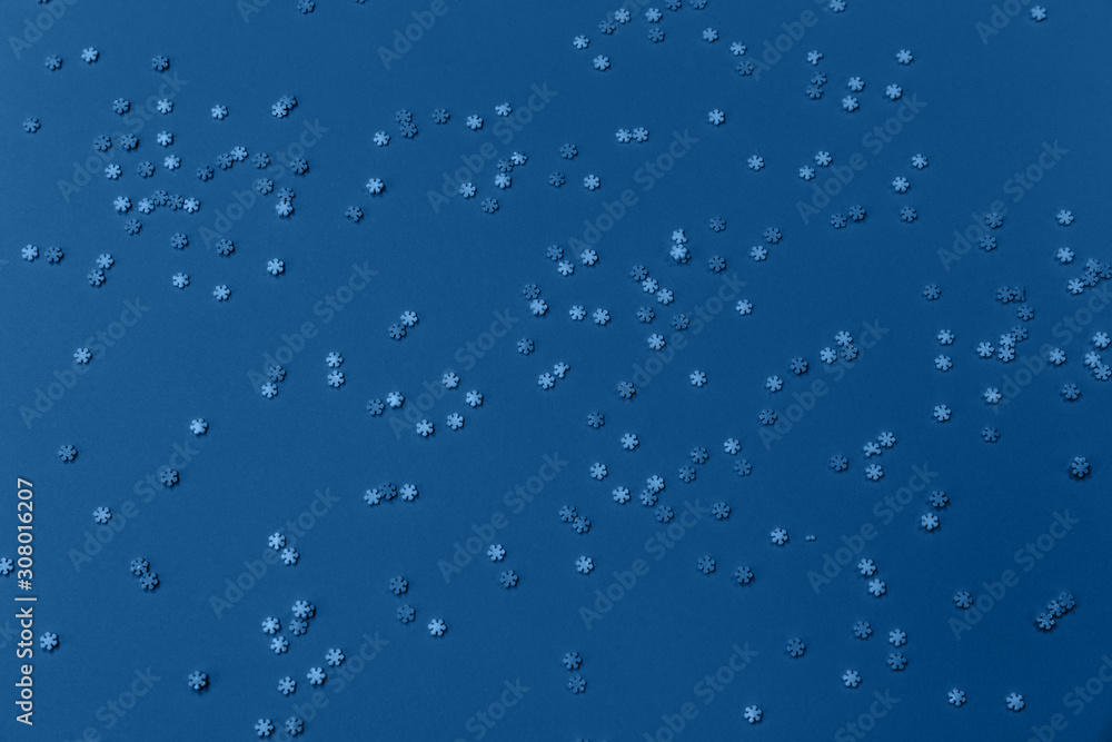 White and blue snowflakes sprinkles on blue. Festive holiday background. Celebration concept. Top view, flat lay. Horizontal. White and blue snowflakes sprinkles on blue. Festive holiday background. Celebration concept. Top view, flat lay. Horizontal.