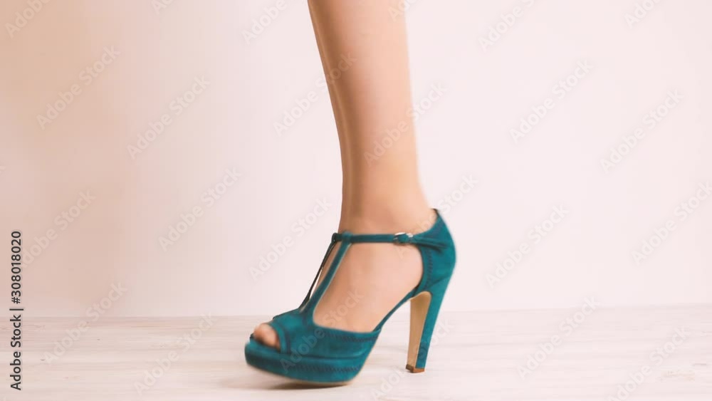 Beautiful turquoise shoes with high heels on women standing, then changing her position. angry knocking her toe on the floor. 4k close-up showing her legs on white background Beautiful turquoise shoes with high heels on women standing, then changing her position. angry knocking her toe on the floor. 4k close-up showing her legs on white background