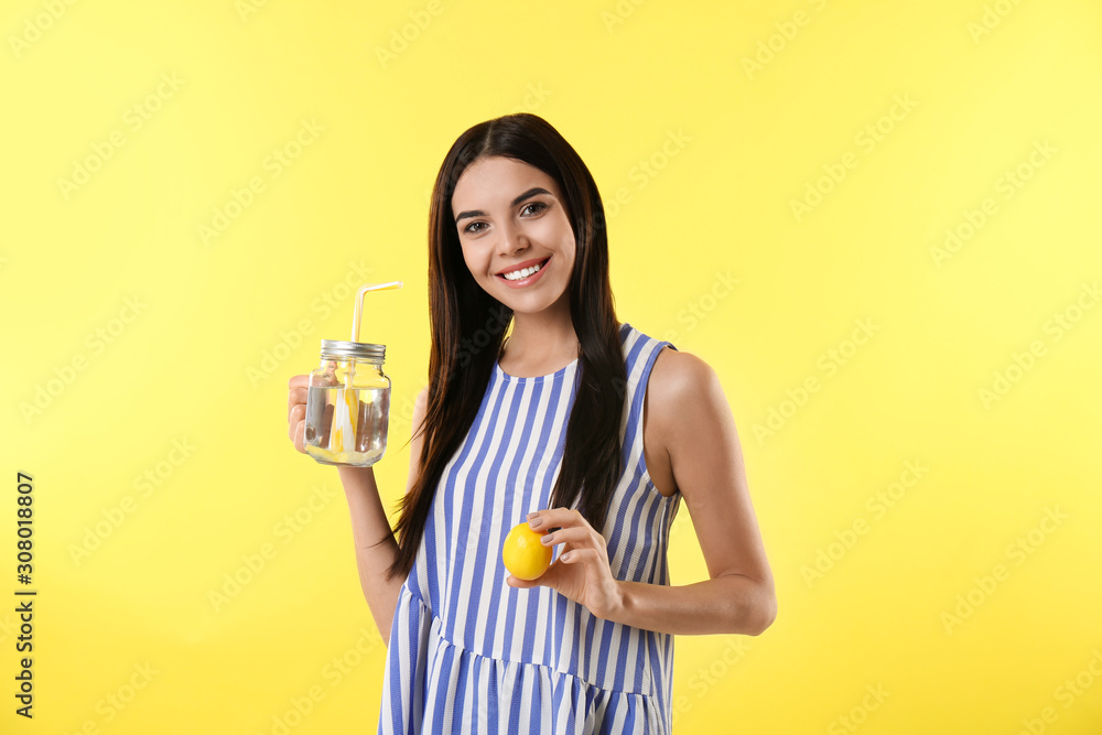 Beautiful young woman with tasty lemon water and fresh fruit on yellow background Beautiful young woman with tasty lemon water and fresh fruit on yellow background