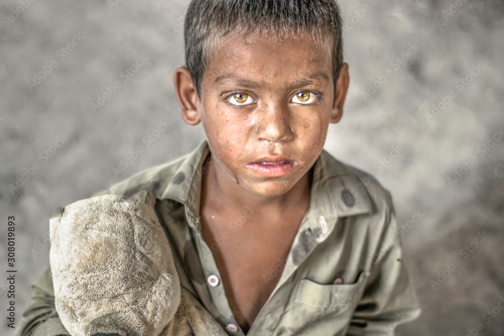 closeup of a poor staring hungry orphan boy in a refugee camp with sad  expression on